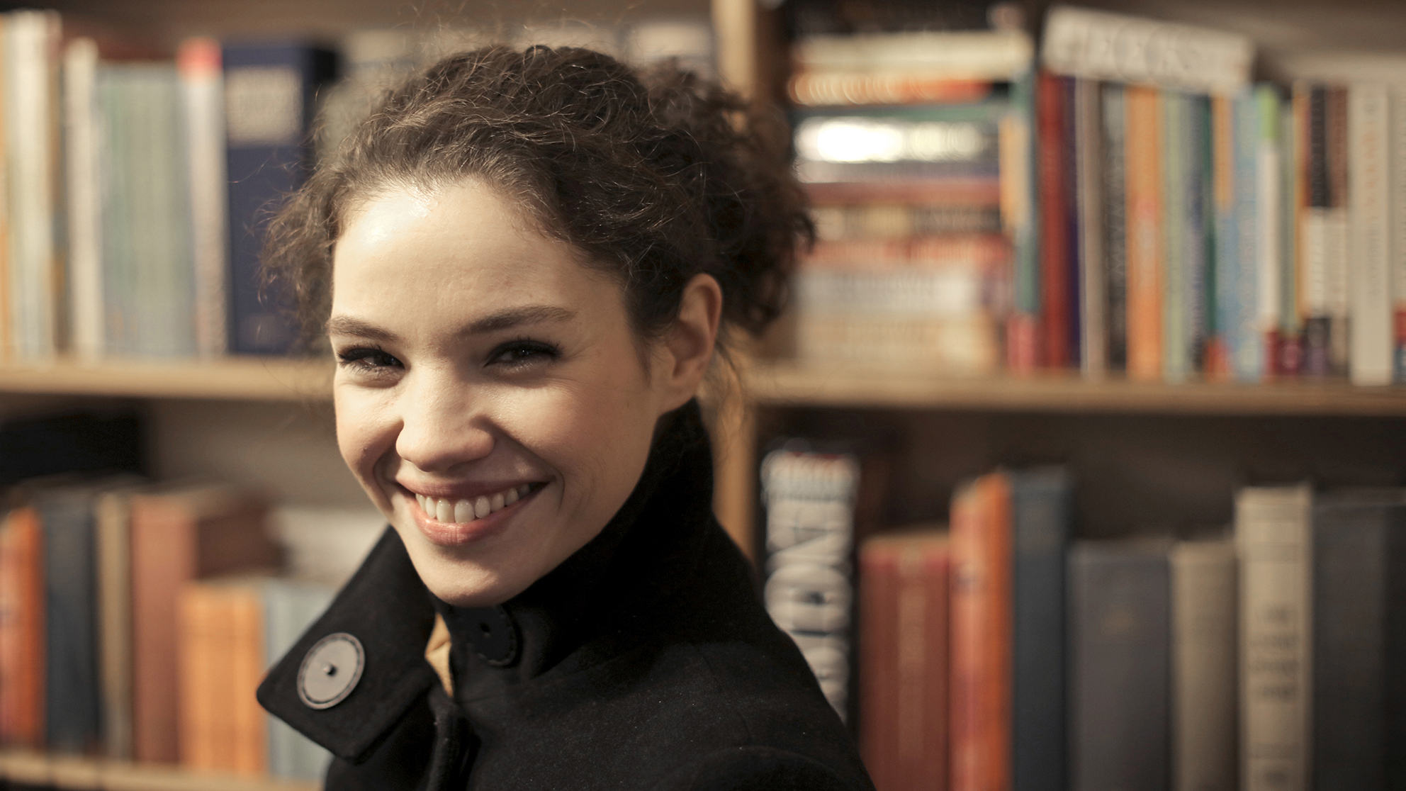 Une jeune femme souriante dans une bibliothèque